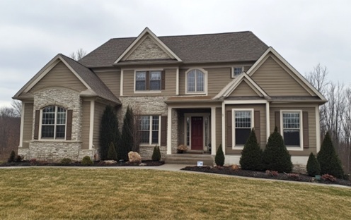 Large suburban home with tan vinyl siding and stone accents, featuring a red front door and landscaped front yard in Columbus, OH.